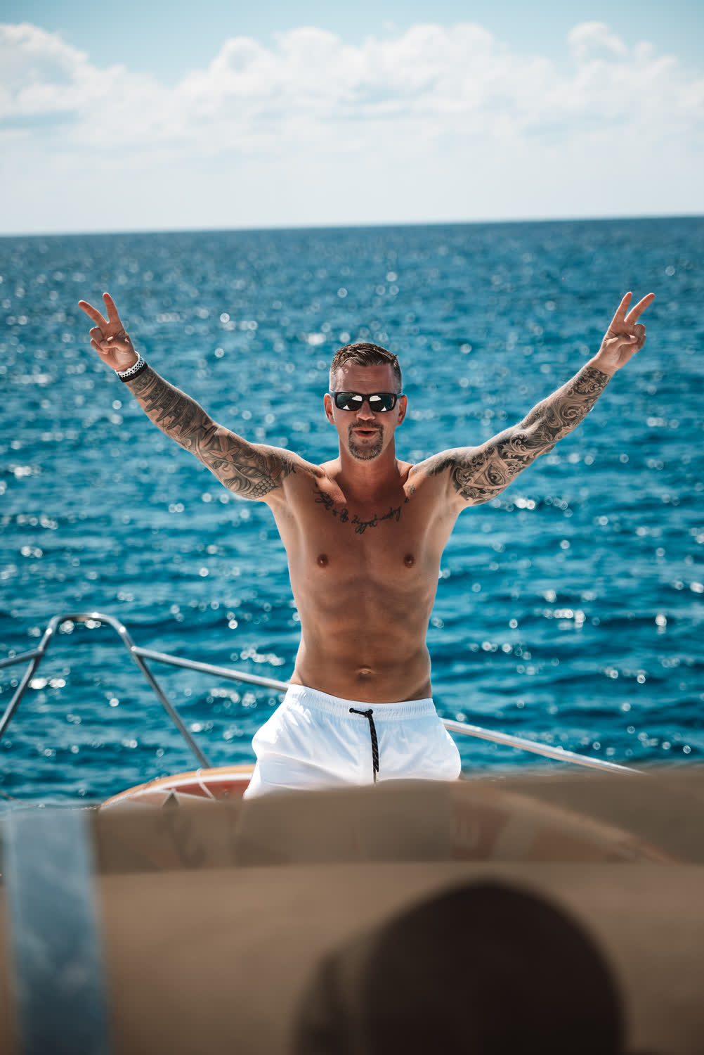 Teilnehmer mit ausgebreiteten Armen auf der Yacht