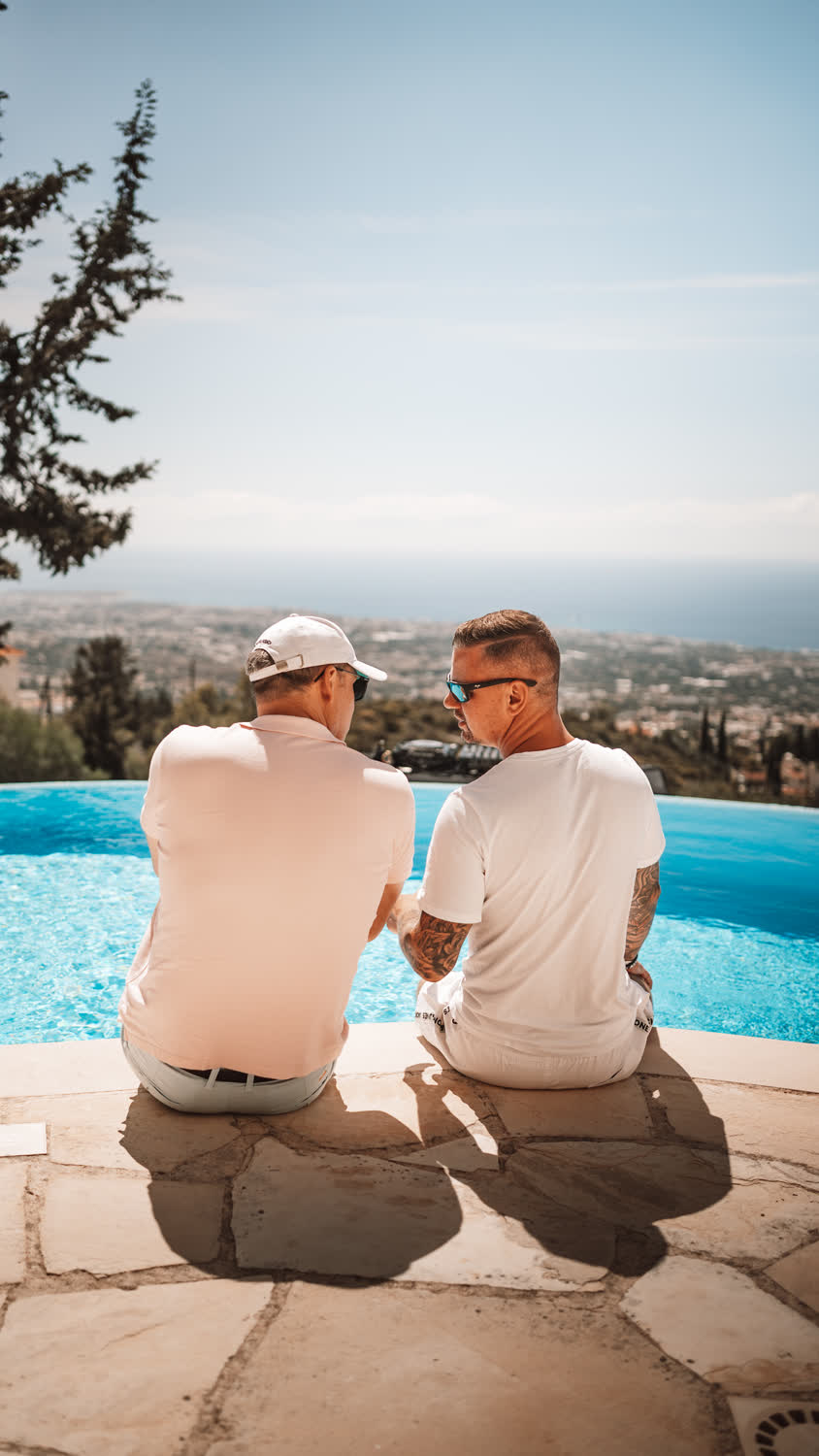 Zwei Teilnehmer am Infinity-Pool mit Blick über Paphos